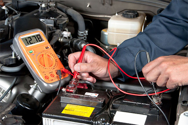 Technician testing a vehicle battery with a multimeter